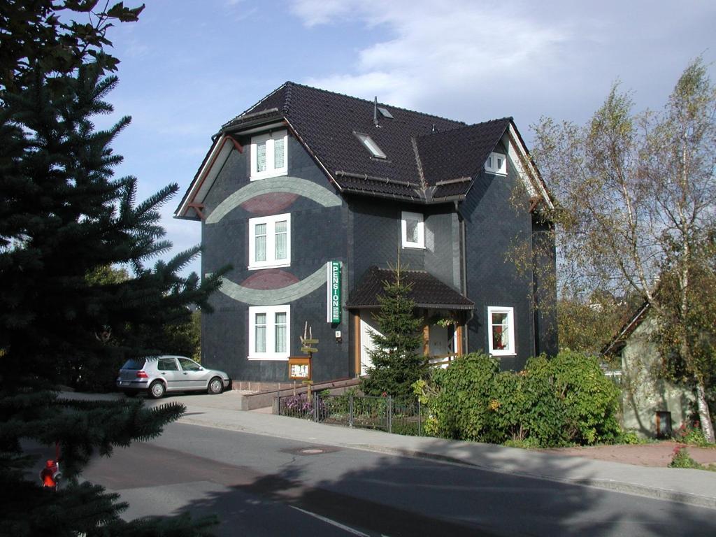 een zwart huis met een auto ervoor geparkeerd bij Aktiv Pension in Oberhof