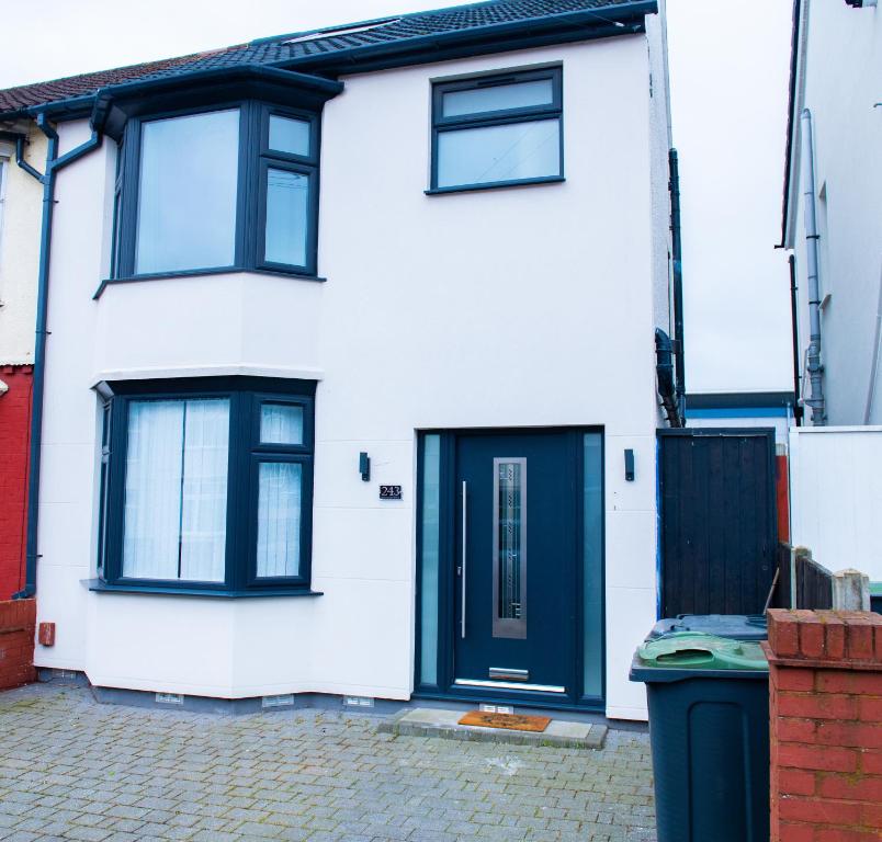 a white house with a black door and a trash can at Newly Refurbished - Affordable Four Bedroom Semi-Detached House Near Luton Airport and Luton Hospital in Luton