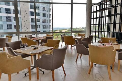 un restaurante con mesas, sillas y ventanas grandes en Sandton Serenity: UltimateGetaway 2, en Johannesburgo