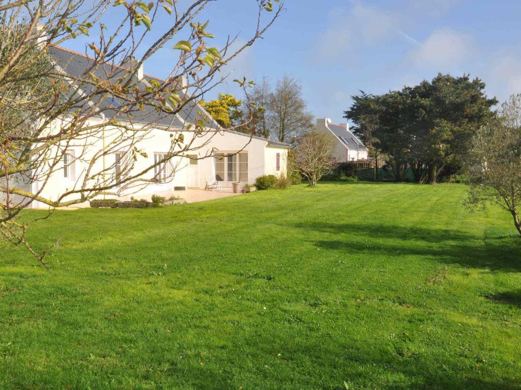 une maison dans une cour avec une pelouse verte dans l'établissement Maison spacieuse pour 9 avec grand jardin, proche plage des Grands Sables! - FR-1-418-18, à Locmaria