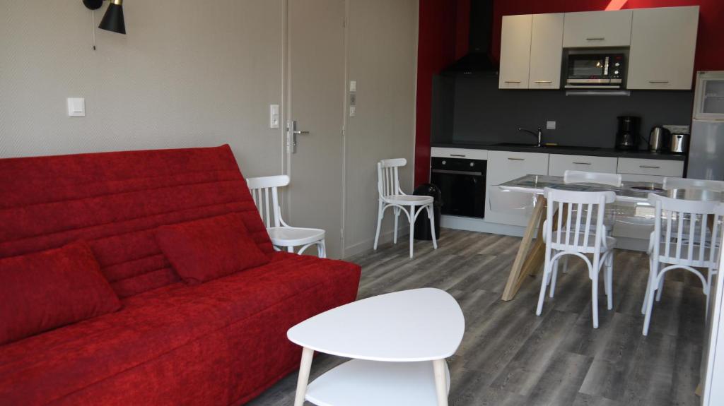 un salon avec un canapé rouge et une cuisine dans l'établissement Appart 4/6 pers proche centre et acces direct plage : Ouessant, à La Bernerie-en-Retz