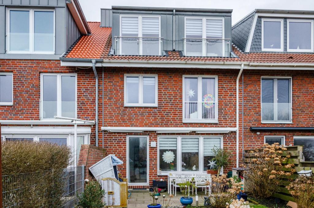 a red brick house with white windows and a patio at Ferienhaus Raschke in Norderney
