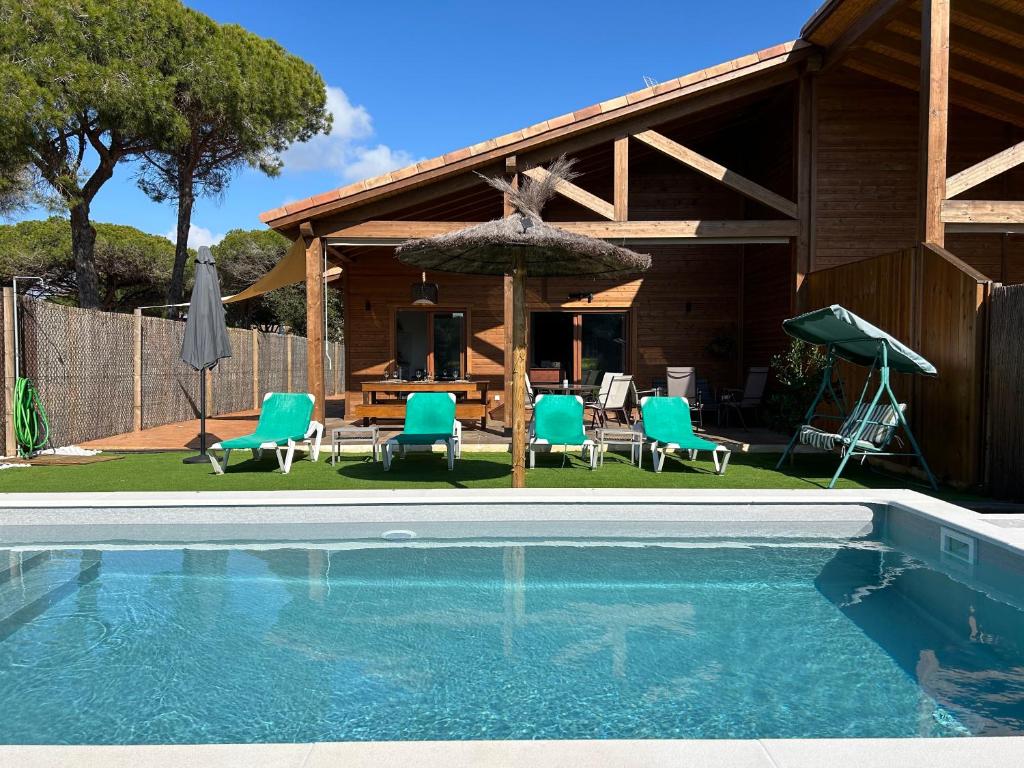 Casa con piscina, sillas y sombrilla en Villas Magnolia y Brezo, en Chiclana de la Frontera