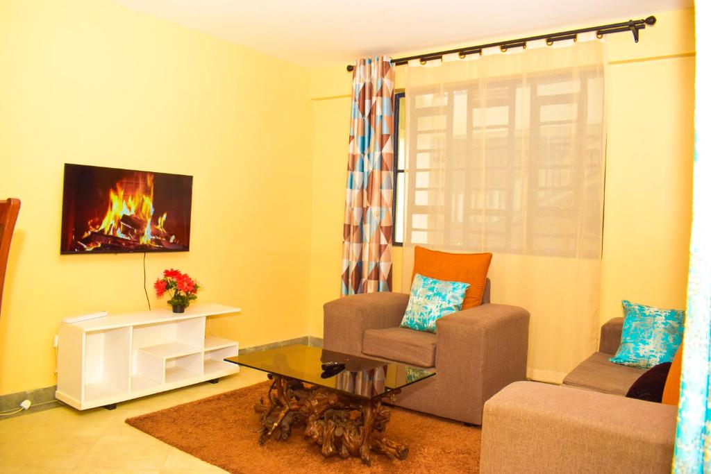 a living room with a couch chair and a fireplace at Lighthomes Two Bedroom Thika CBD in Thika