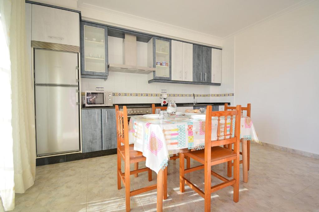 a kitchen with a table and chairs and a refrigerator at Apartamentos en Playa de Montalvo in Sanxenxo