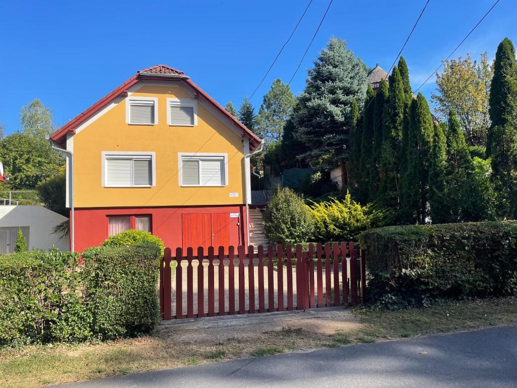 ein gelbes und orangefarbenes Haus mit einem Holzzaun in der Unterkunft Ili Vendégház in Zalakaros