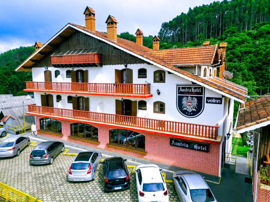 a building with cars parked in a parking lot at VELINN Áustria Hotel Monte Verde in Monte Verde