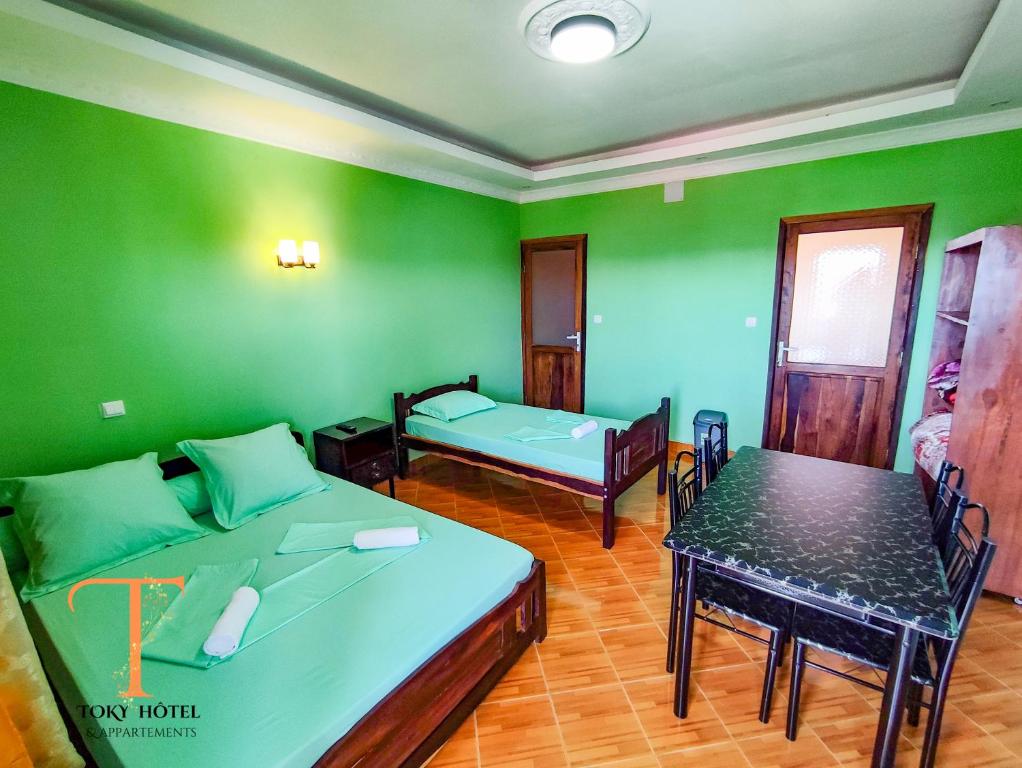 een kamer met twee bedden en een tafel erin bij TOKY Hôtel in Antsirabe