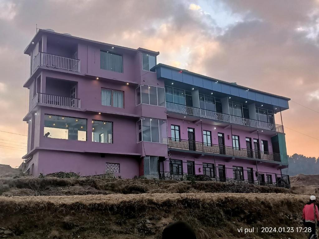 Un bâtiment violet avec des personnes debout devant lui dans l'établissement Hotel heavenly heights, à Dhanaulti