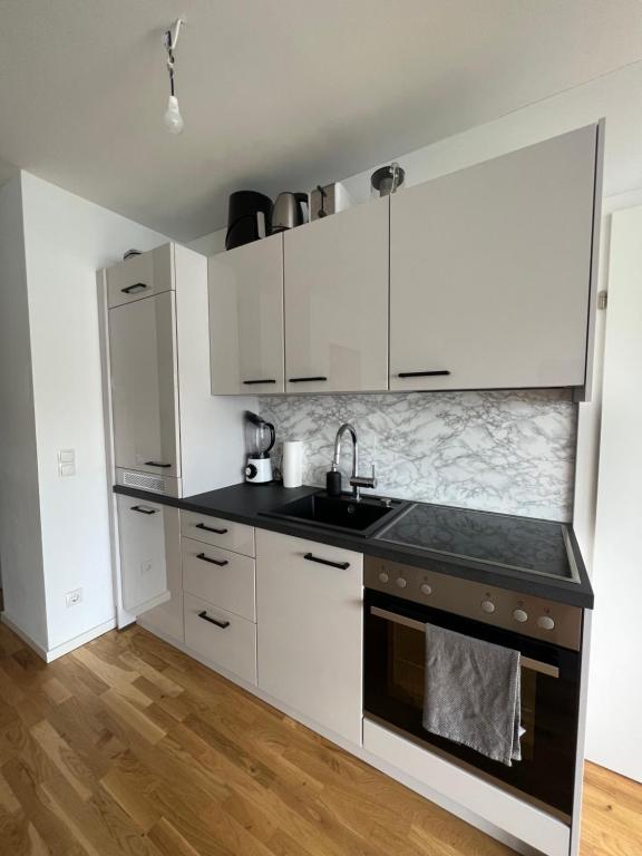 una cocina con armarios blancos y fregadero en Modernes & stillvolles Apartment en Viena