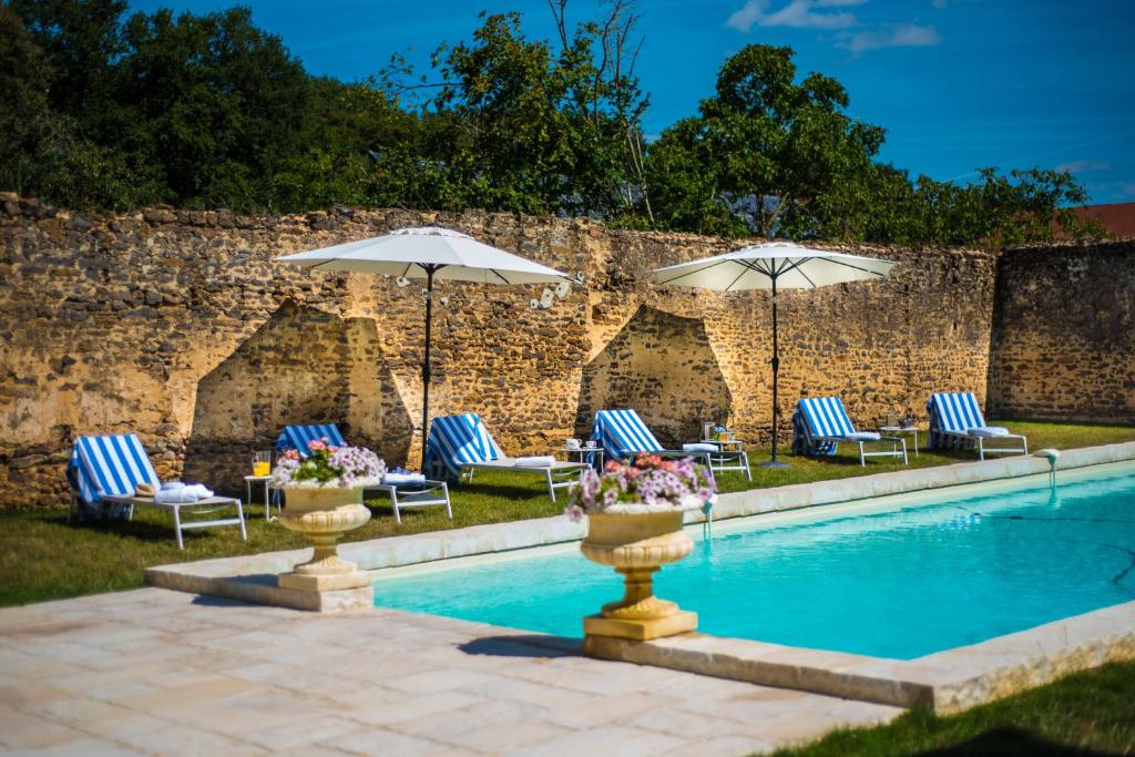 uma piscina com cadeiras e guarda-sóis ao lado de uma parede em Hôtel du Domaine de La Groirie - Le Mans em Trangé