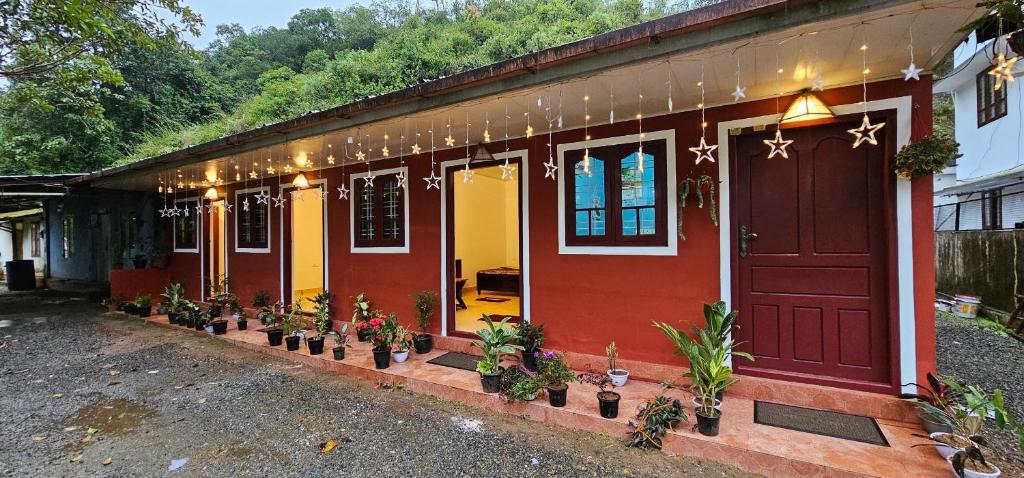 a red house with potted plants in front of it at mountainfog in Devikolam