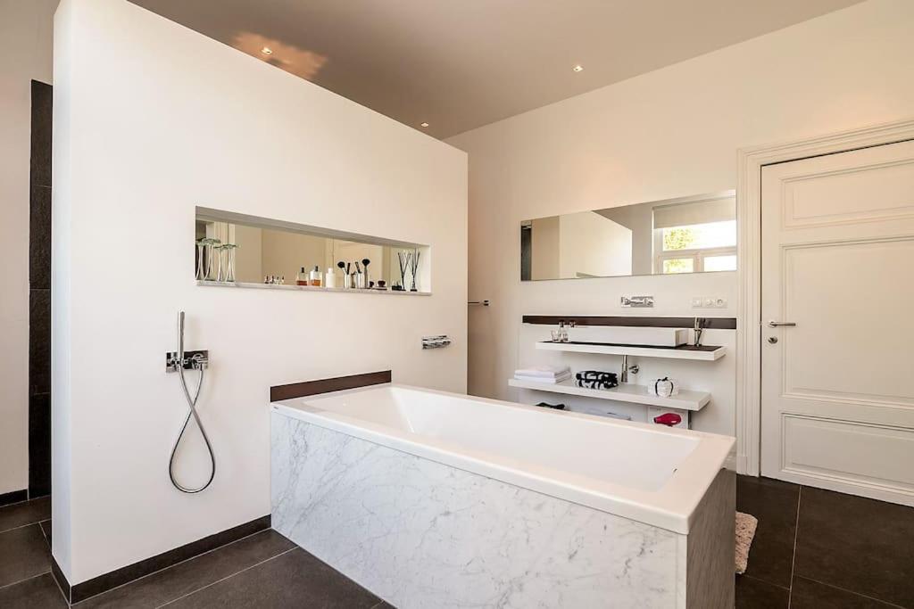 a white bathroom with a tub and a sink at Bohemian Residence in Maastricht