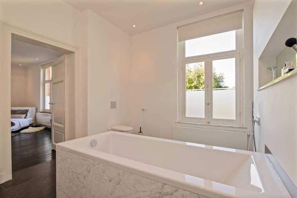 a large white bath tub in a bathroom with a window at Bohemian Residence in Maastricht
