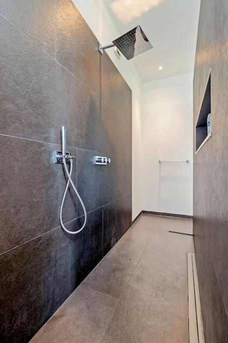 a bathroom with a shower with a hose on the wall at Bohemian Residence in Maastricht