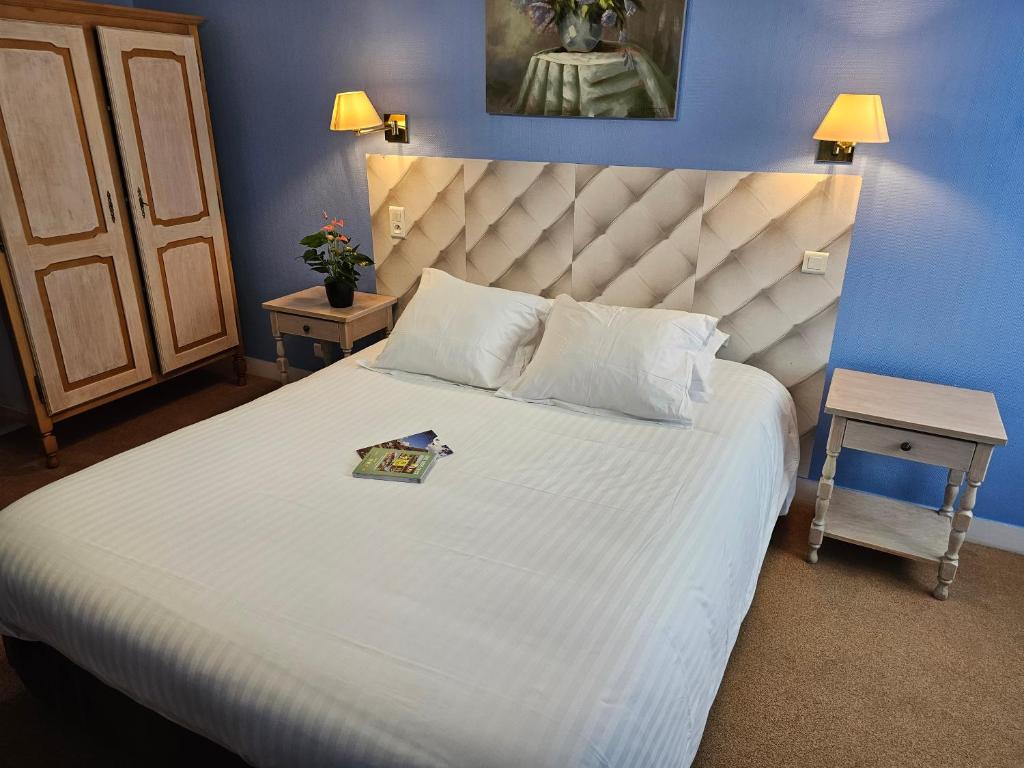 a bedroom with a large white bed with a blue wall at Logis Hôtel Restaurant L'Unique in Ménesqueville