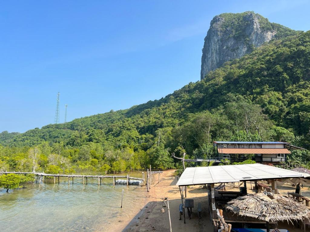 a building on the shore of a river with a mountain at Baan Plai Laem Homesty in Koh Phaluai
