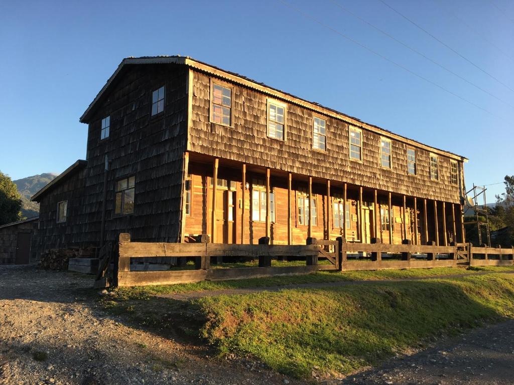 ein großes Holzgebäude auf einem Feld in der Unterkunft La Casona Puelo Lodge in Cochamó