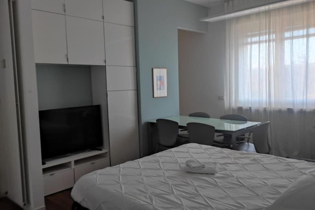 1 dormitorio con cama, mesa y TV en Appartamento - Rho Centro 6 -, en Rho