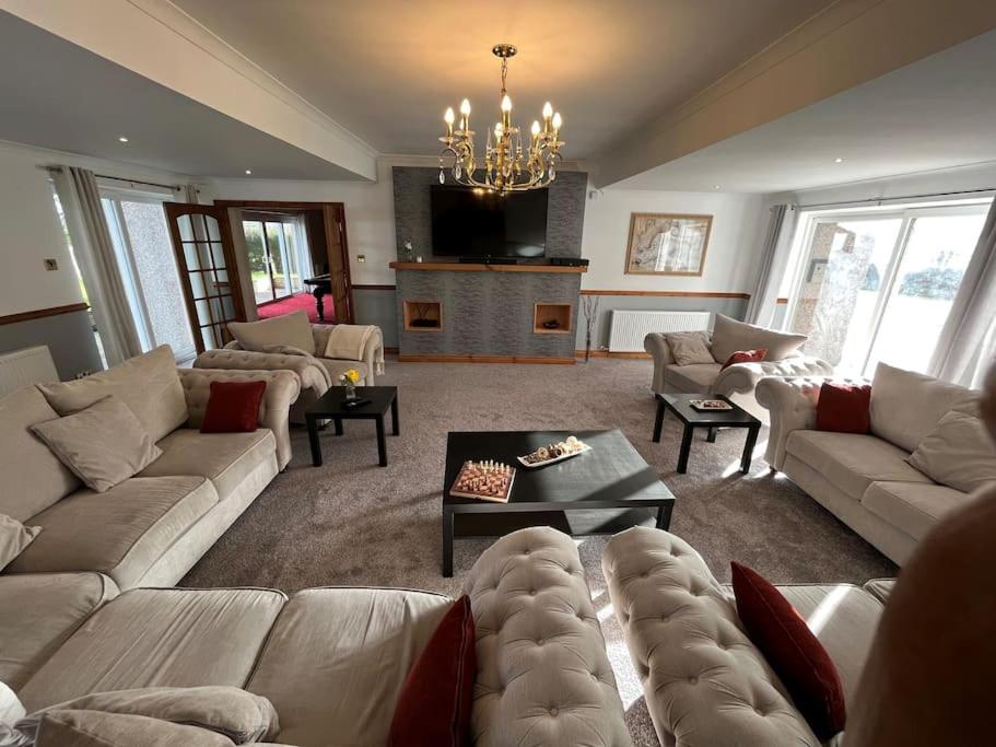 een grote woonkamer met banken en een open haard bij Luxurious 5 bedroom house with games room in Kingholm Quay