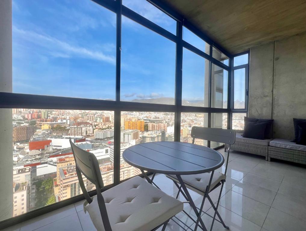 a table and chairs in a room with a large window at 29 Floor. Home Suite Home in Santa Cruz de Tenerife