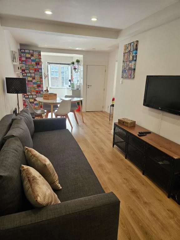 uma sala de estar com um sofá e uma televisão de ecrã plano em Lisboa Bridge Spot em Lisboa