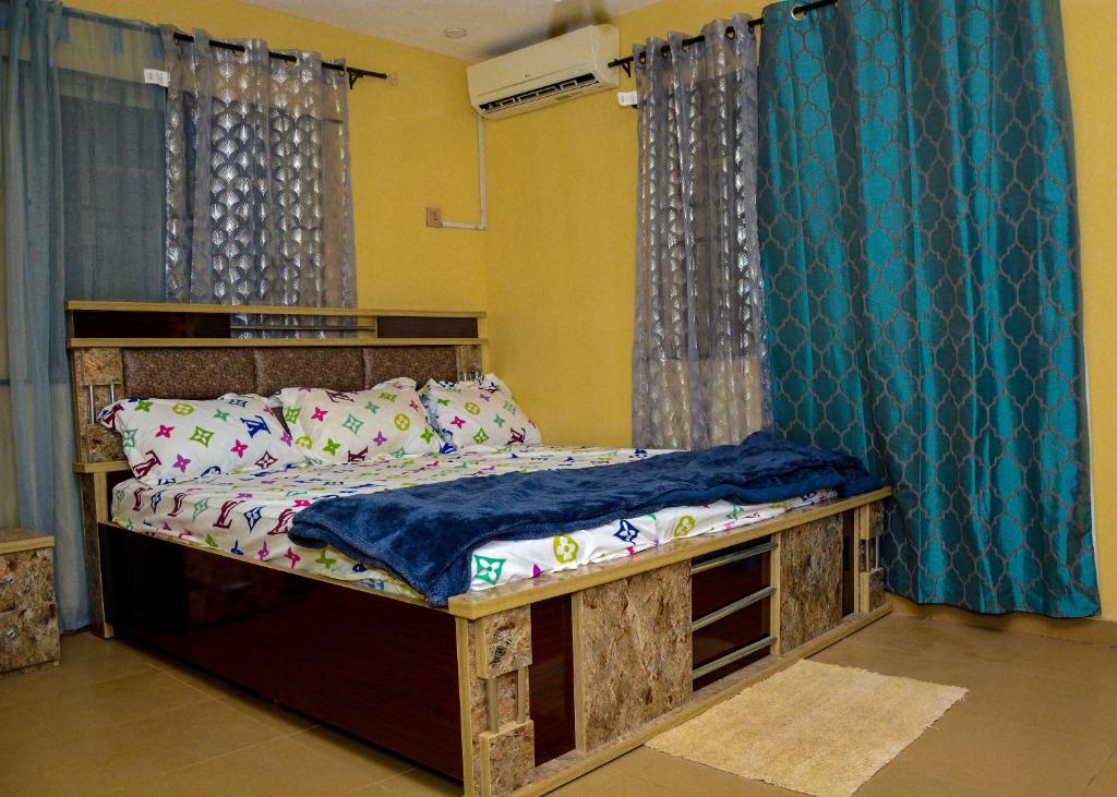 a bedroom with a wooden bed with blue curtains at Rehoboth hotel, Apartment and Event services in Suberu Oje