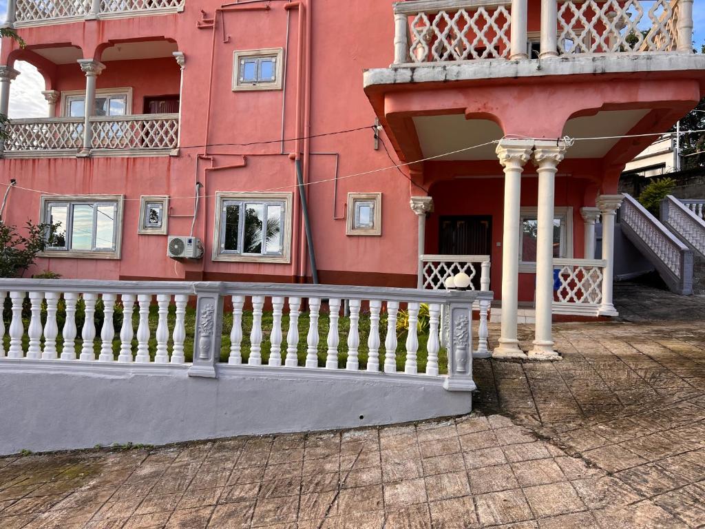 a pink building with a white fence in front of it at Delornya Complex in Freetown