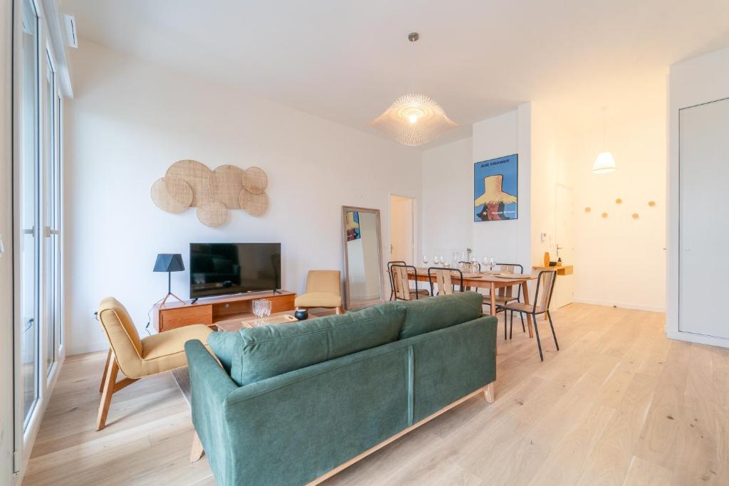 un salon avec un canapé vert et une salle à manger dans l'établissement L'Exupéry- Parking privé et à 15min de Paris, à Saint-Ouen