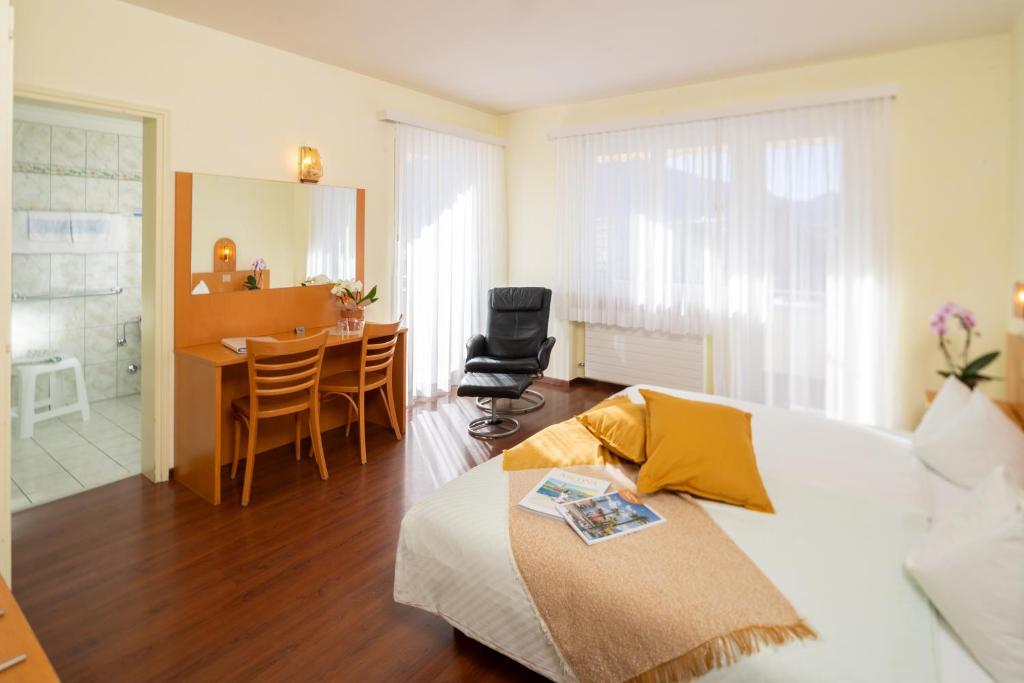 Hotel Rondinella Locarno في لوكارنو: غرفة نوم مع غرفة معيشة وغرفة طعام