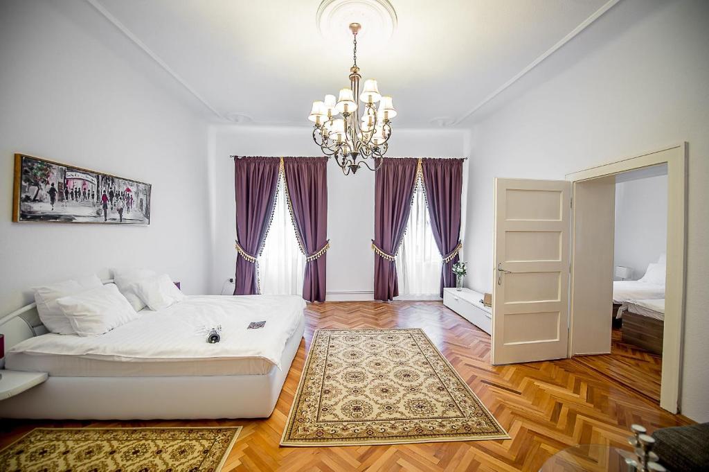 - une chambre avec un lit blanc et un lustre dans l'établissement Apartament Piata Mica, à Sibiu