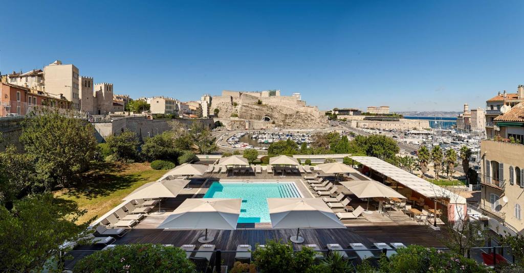 マルセイユにあるラディソン ブルー ホテル マルセイユ ヴュー ポールのプールとパラソル付きのリゾートの空中ビュー