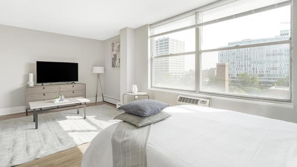 a white bedroom with a bed and a tv at Landing Modern Apartment with Amazing Amenities (ID1222X746) in Chicago