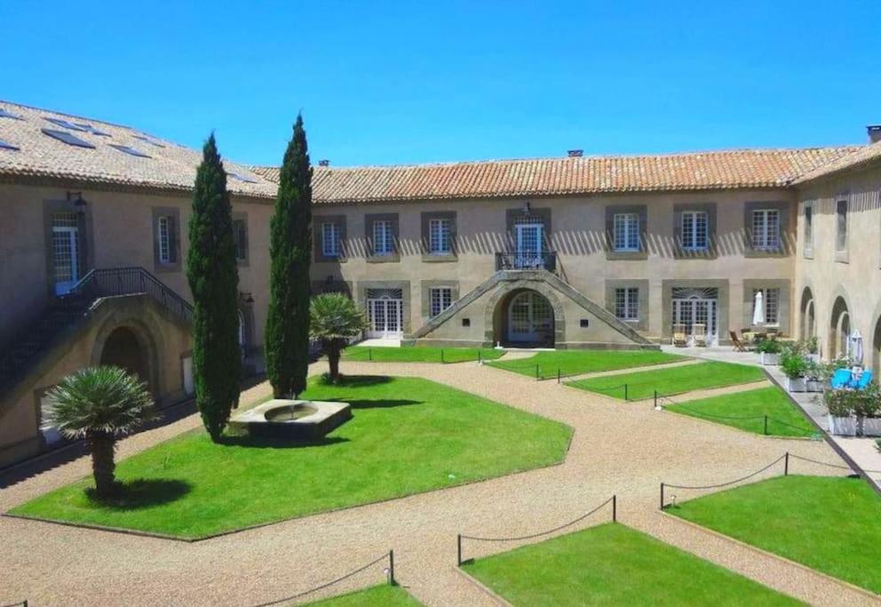 un patio de un edificio con árboles y césped en Château Winery la Batisse le minervois, en Laredorte