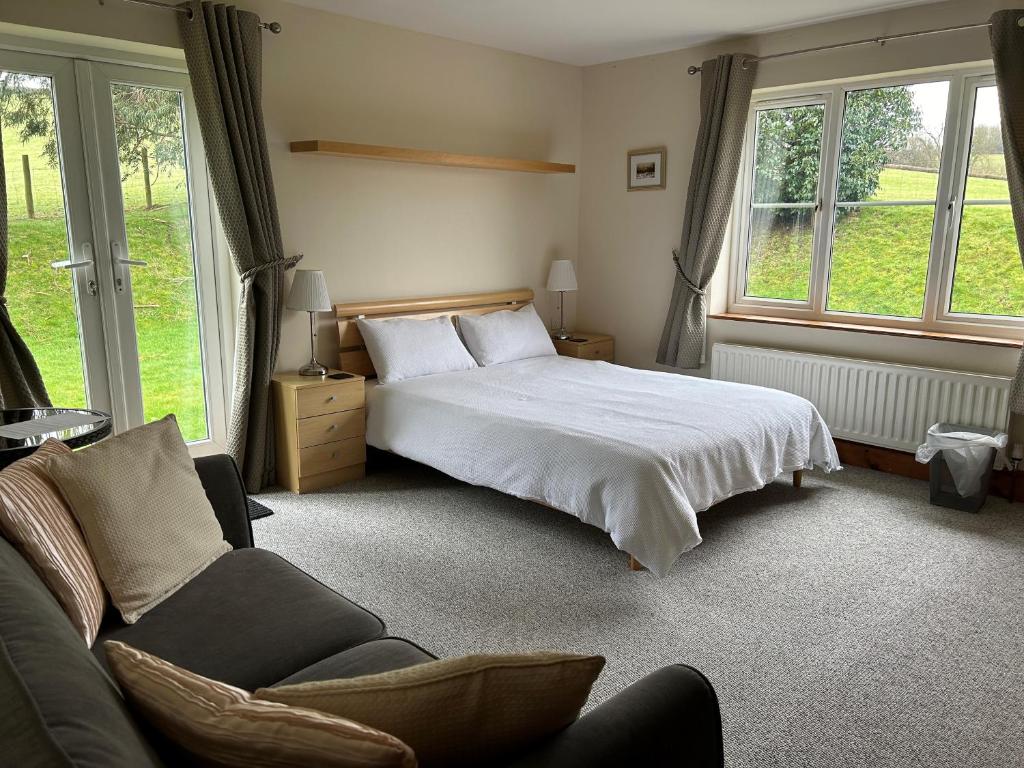 a bedroom with a bed and a couch and windows at Whidlecombe Farm in Priston