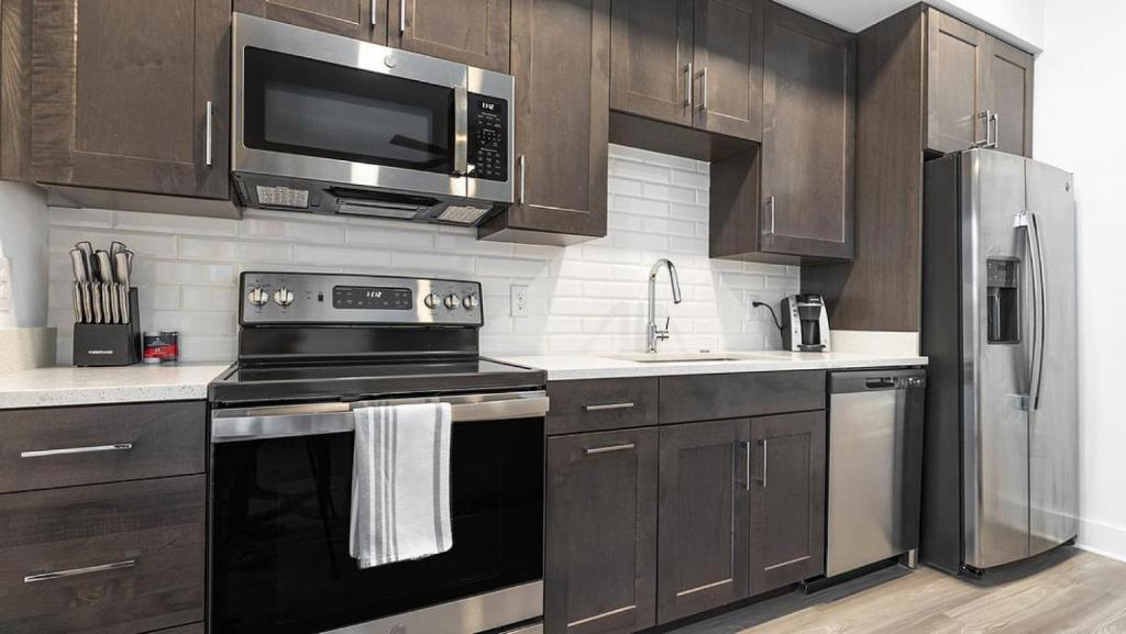 een keuken met roestvrijstalen apparatuur en houten kasten bij Landing Modern Apartment with Amazing Amenities (ID7588X22) in Fort Myers