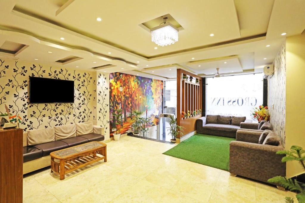 Hotel tu casa International Near Delhi Airport في نيودلهي: غرفة معيشة مع أريكة وتلفزيون