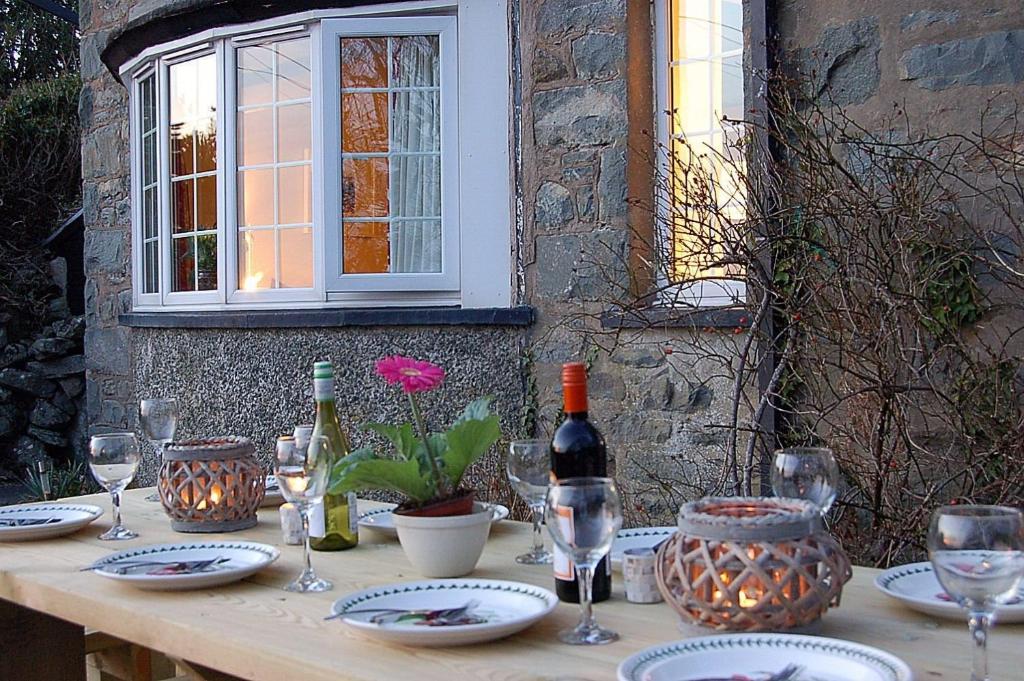 a wooden table with wine bottles and glasses on it at Minafon near Barmouth in Llanaber