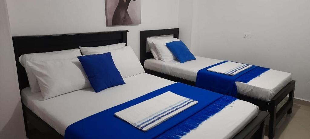 Duas camas com almofadas azuis e brancas num quarto em Hotel La Guajira - Centro Historico em Ríohacha