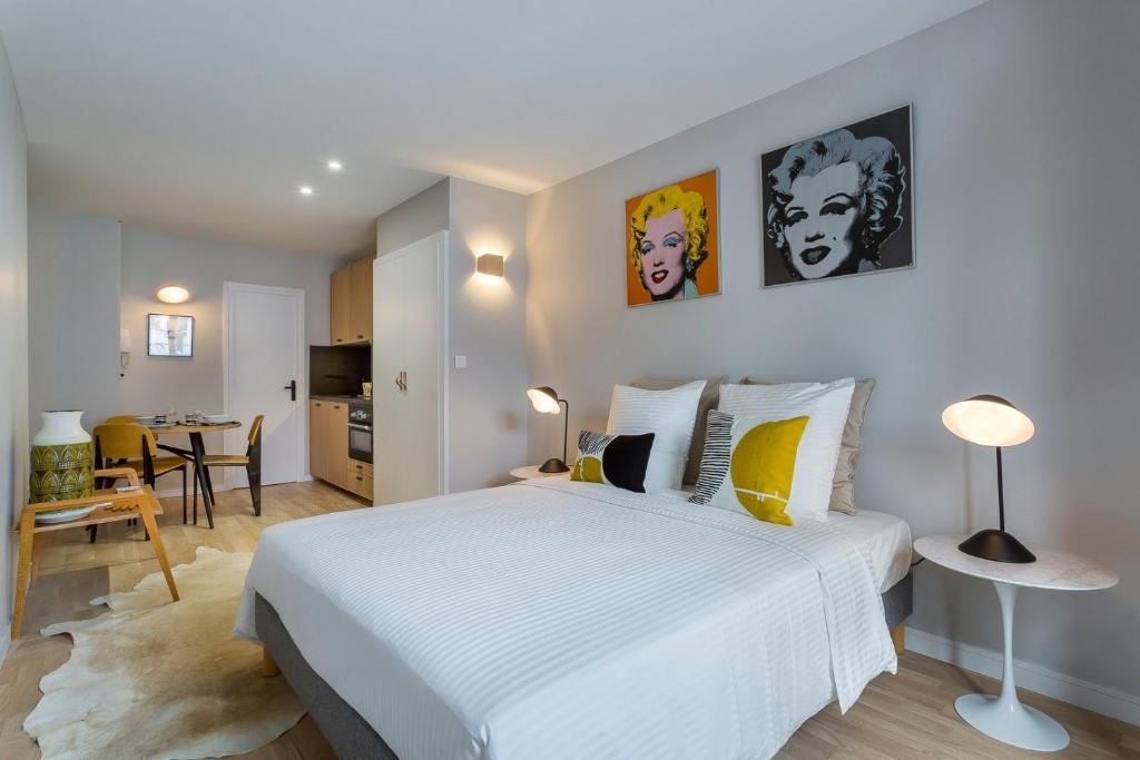a bedroom with a large white bed and a kitchen at Gasparin - Studio - Lyon 2 in Lyon