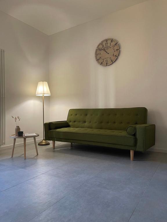 a green couch in a living room with a clock on the wall at Casa Giovanni in Pavia