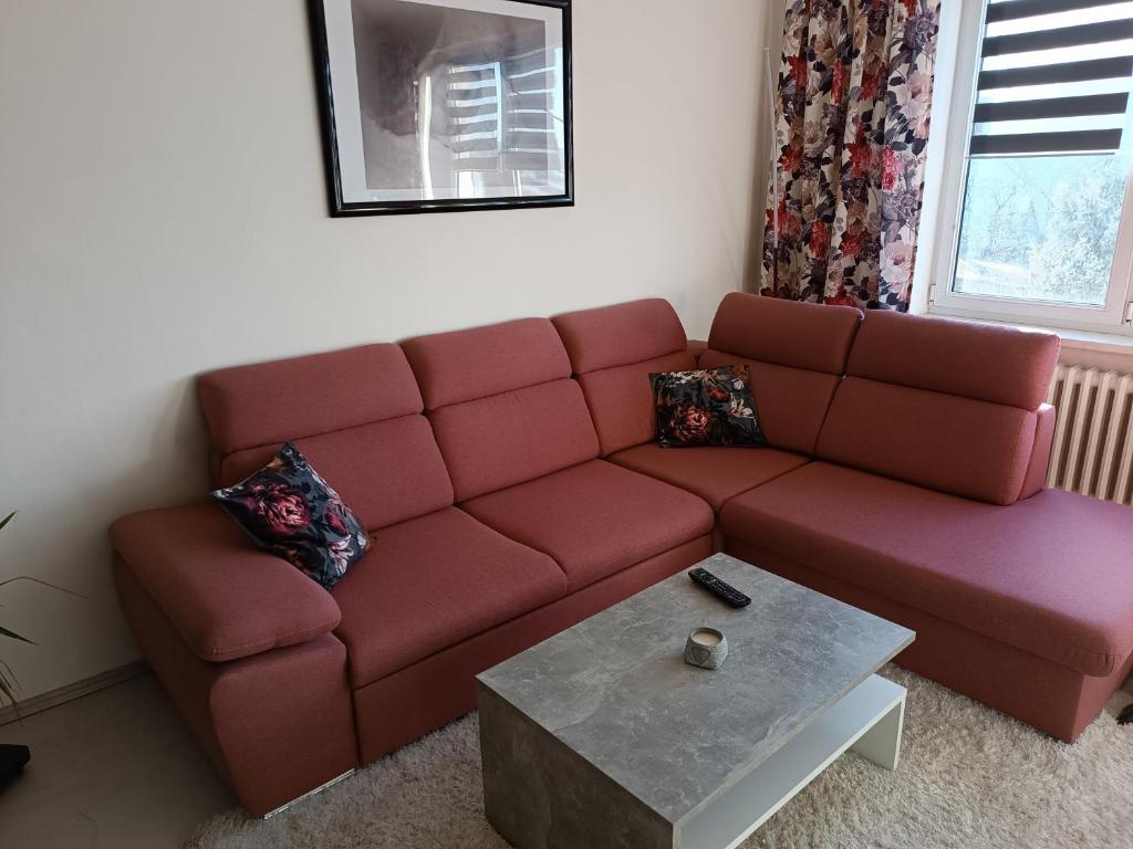 a living room with a red couch and a coffee table at Apartmán Kolářová in Klatovy