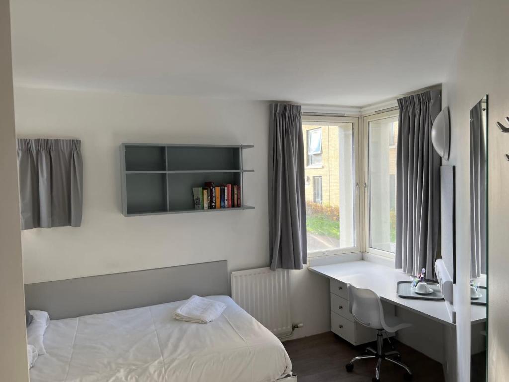 a bedroom with a bed and a desk and a window at Cosy Private Ensuites and Studios in the heart of Cheltenham in Cheltenham
