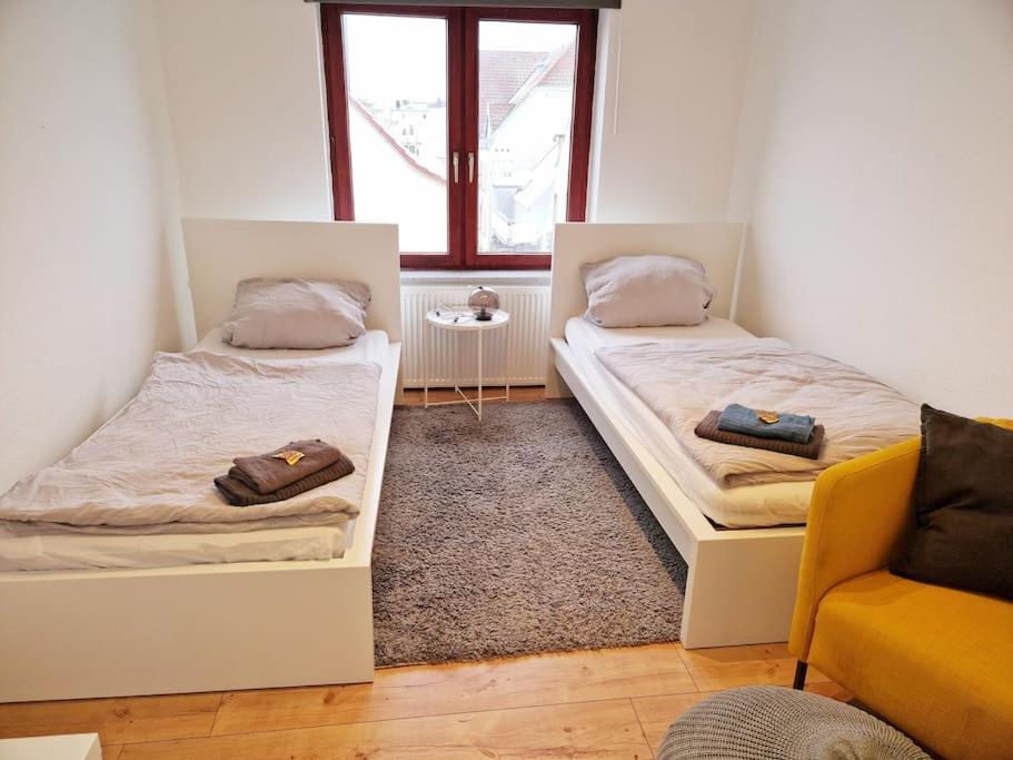 een kamer met 2 bedden, een bank en een raam bij Nordseeluft Apartment in Bremerhaven