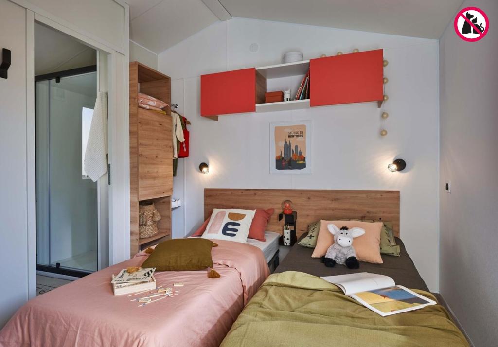 two beds in a room with red cabinets at Camping La Mignardière in Ballan-Miré