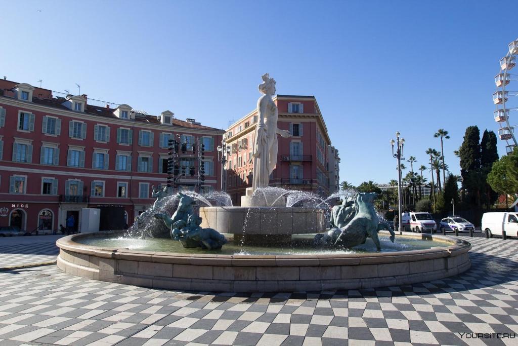 una fuente en medio de una plaza con edificios en Downtown, en Niza