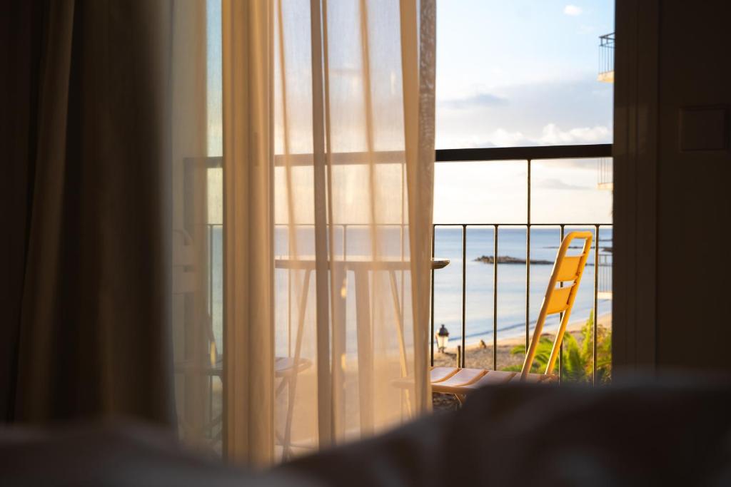 een raam met uitzicht op een strand en een stoel bij Boutique Apartments Marsol Ibiza in Santa Eularia des Riu