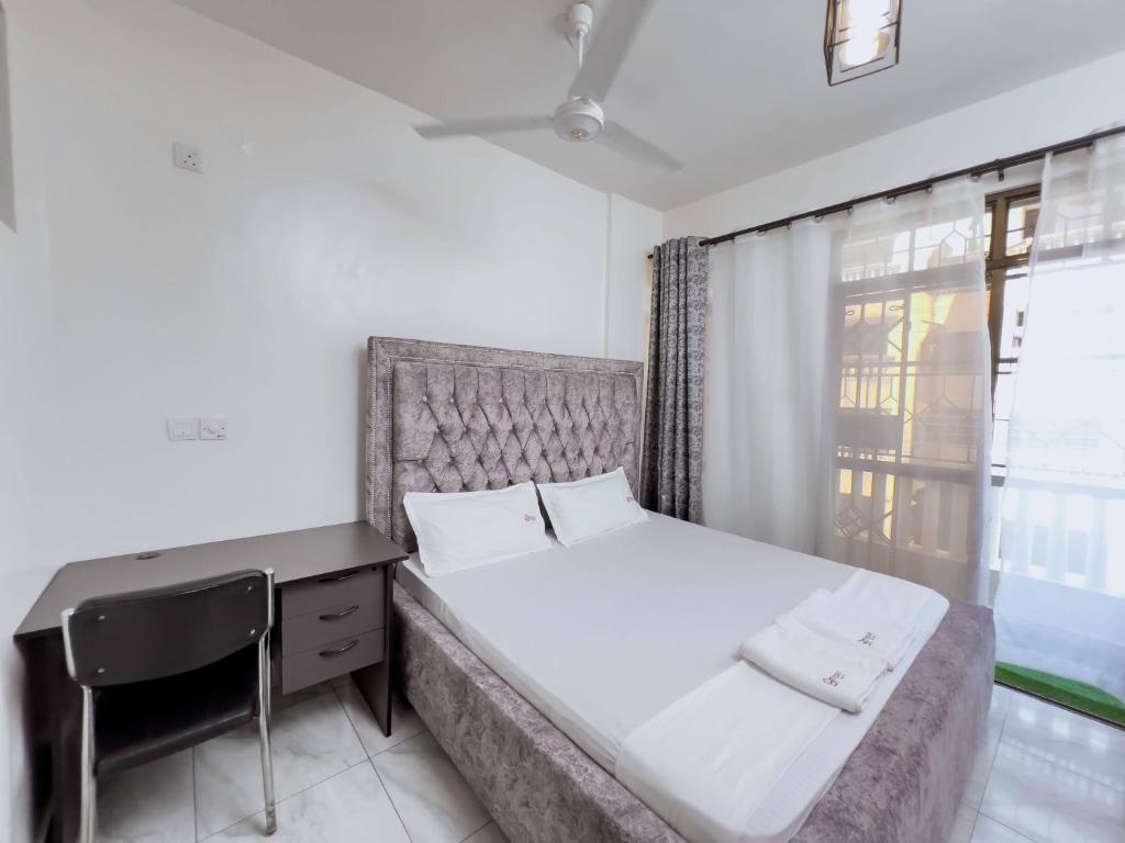 1 dormitorio con cama, escritorio y ventana en beautifully furnished one bedroom apartment in vok off nyali road, en Mombasa