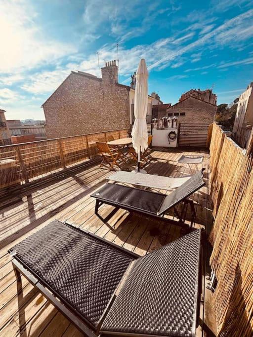 uma varanda com duas mesas e um guarda-sol e cadeiras em Sublime Rooftop Cinq-Avenues Longchamp em Marselha