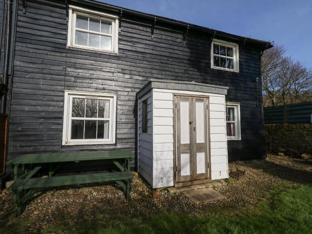mały dom z zieloną ławką przed nim w obiekcie Chenies w mieście Weymouth